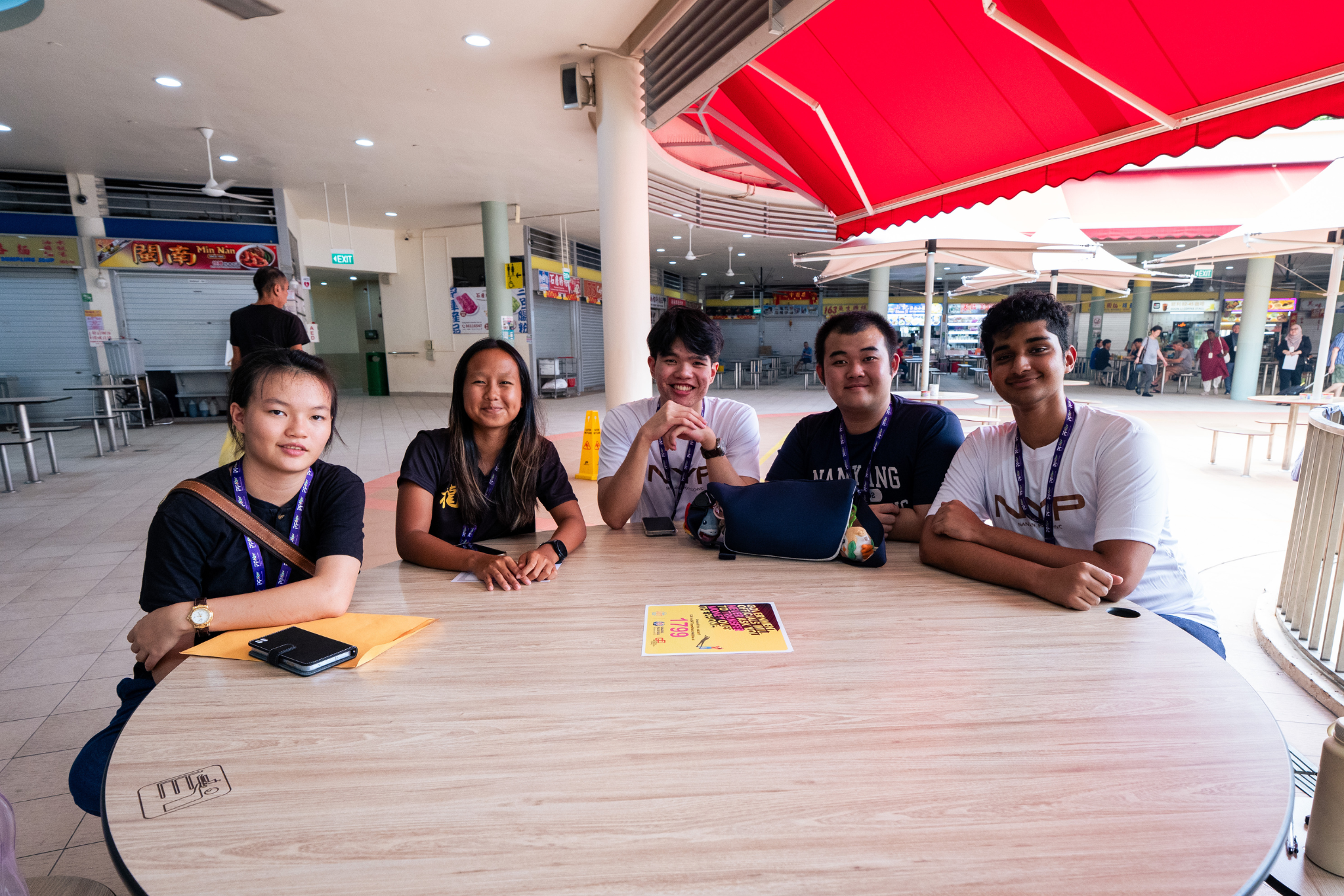 Student delegates engage members of the public in conversations during a street interview activity at Tiong Bahru Market.